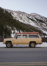 vintage suburban parked in front of a snow covered mountain 