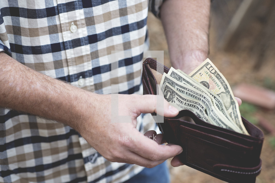 a man holding a wallet full of cash 