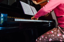 a girl child in pajamas playing a piano 