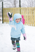 a girl child in mittens playing in the snow 