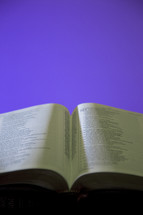 an open Bible on a stack of Bibles 