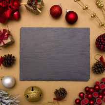 slate surrounded by Christmas ornaments 