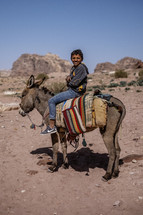 a boy riding on a donkey 
