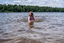 little girl swimming in a lake in summer 