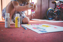 a toddler girl painting with paints 