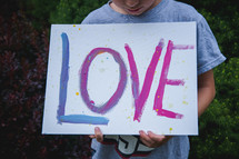 a boy holding a hand painted sign with the word love 