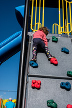 toddler climbing a climbing wall on a playground 
