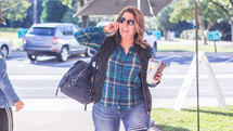 a woman taking on a cellphone and carrying a to go coffee cup 