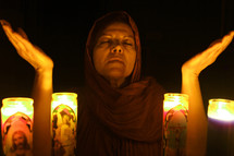 woman in prayer by candles