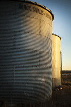 Metal grains silos in a field.