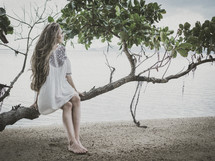 Woman sitting on tree by the beach