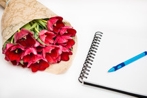 Flat lay of red bouquet tulips isolated on white with notebook and pen with empty place for your text