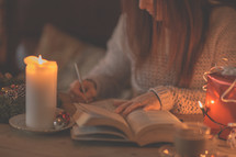 a woman reading a Bible and writing in a journal at Christmas 