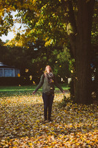 a woman throwing fall leaves