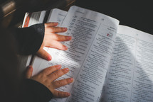 a child's hands on the pages of a Bible 