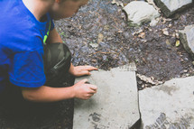 boy child looking under rocks 
