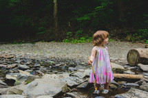 toddler girl walking across rocks in a stream 