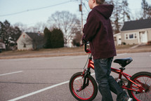 A boy riding a bike in a parking lot on a spring day.