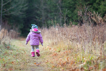 a toddler walking through a field 