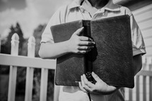 a boy holding a Bible close to his chest 