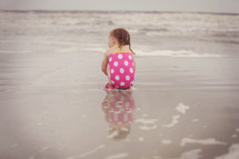 a child sitting on wet sand 