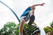 a boy child jumping off playground equipment 