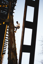 a man climbing a rusty bridge 