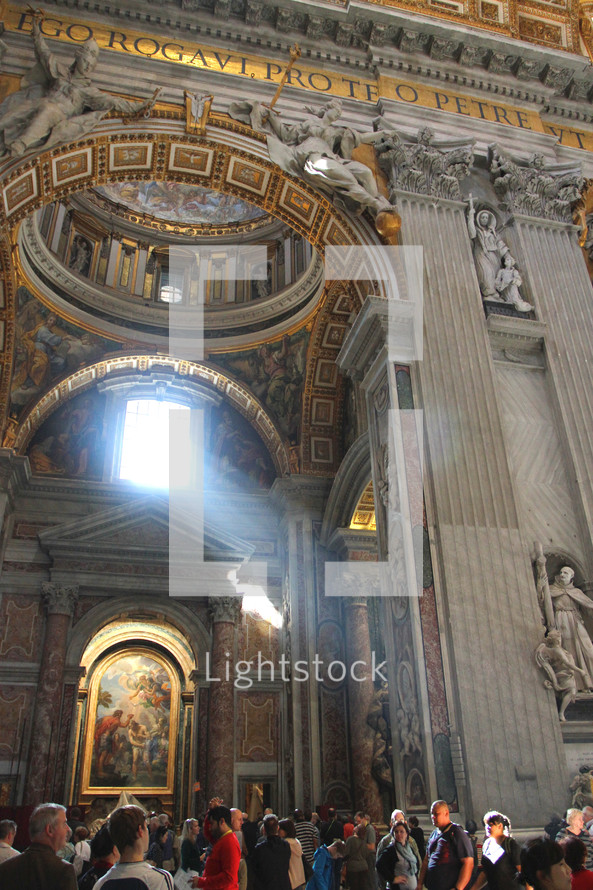 Light streams through the window onto the tourists inside St. Peter's Basilica in Vatican City