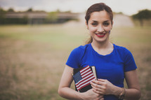 Woman holding a Bible, American flag, and a temporary tattoo 