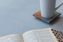 Open bible next to a coffee cup with copy space