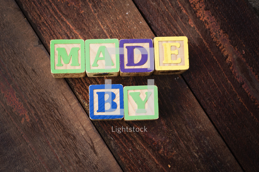 "Made By" spelled out with colorful wooden children's blocks.