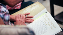 An elderly woman reading a magazine article "Experiencing God in Your Daily Life" 