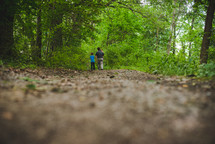 father and children walking on a path through the woods 