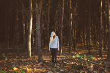 blonde woman standing alone in a forest 