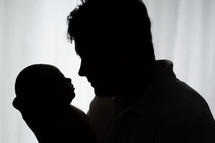 silhouette of a father holding his newborn baby 