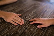 hands of a couple on a wooden table 