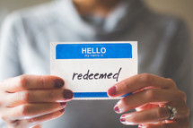 woman holding a name tag with the word redeemed 
