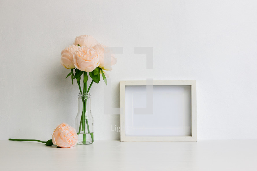 peach flowers in a vase and blank frame 