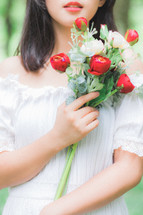 a woman holding red and white flowers 