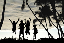 kids jumping and silhouette of palm trees 