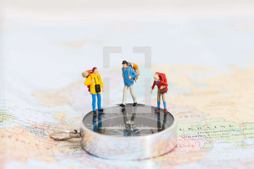 miniature figurines standing on a map and compass