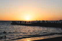 silhouettes of people on a jetty in Hawaii at sunset 