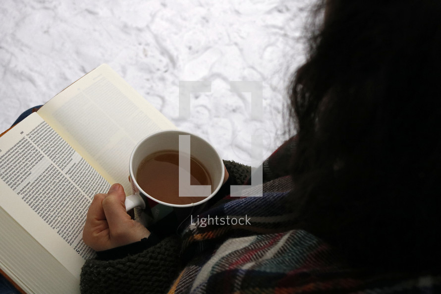 a woman reading a Bible with tea 