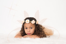 A young girl wearing a wreath of flowers on her head.