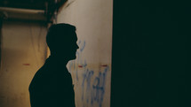 side profile of a man standing in a dark alley at night 