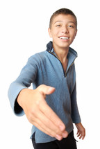 Smiling boy greets with his hand on a white background