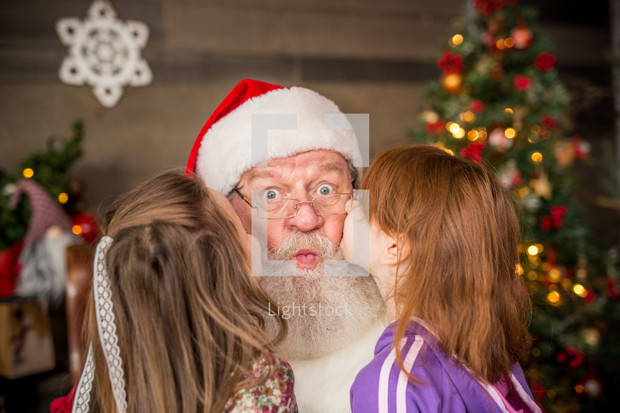 toddler girls kissing Santa Claus 