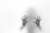 child's hands through frosted glass