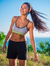 Portrait of young pretty sporty athletic woman on sea summer nature background. Lady after workout.