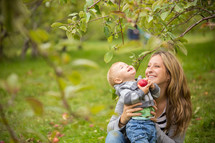 mother and son holding an apple outdoors 
